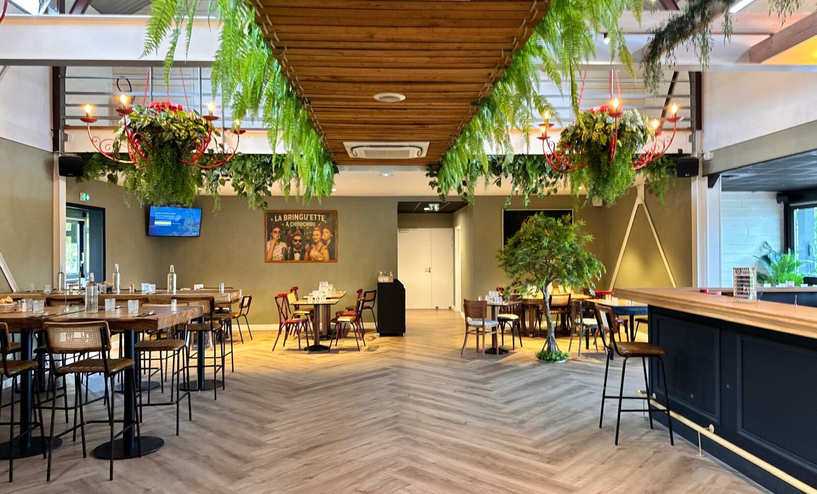Salle principale de La Bringu'ette à Chouchou (bar-restaurant à Beaucouzé, 10min d'Angers) avec une belle décoration : des tables hautes, des tables standards, des télévisions, de la végétation, un bar de 7 mètres de long.